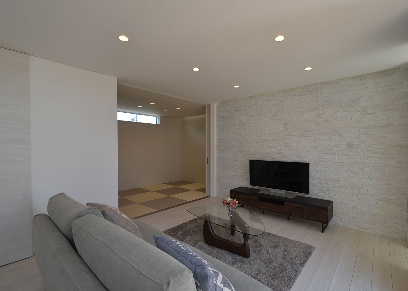 Touch House（タッチハウス）【デザイン住宅、夫婦で暮らす、間取り】テレビ背面の壁はタイル貼りにして間接照明を取り入れ、高級感をプラス。タイルの裏には畜熱体を入れることで、室内の温かさを保てるようになっている。