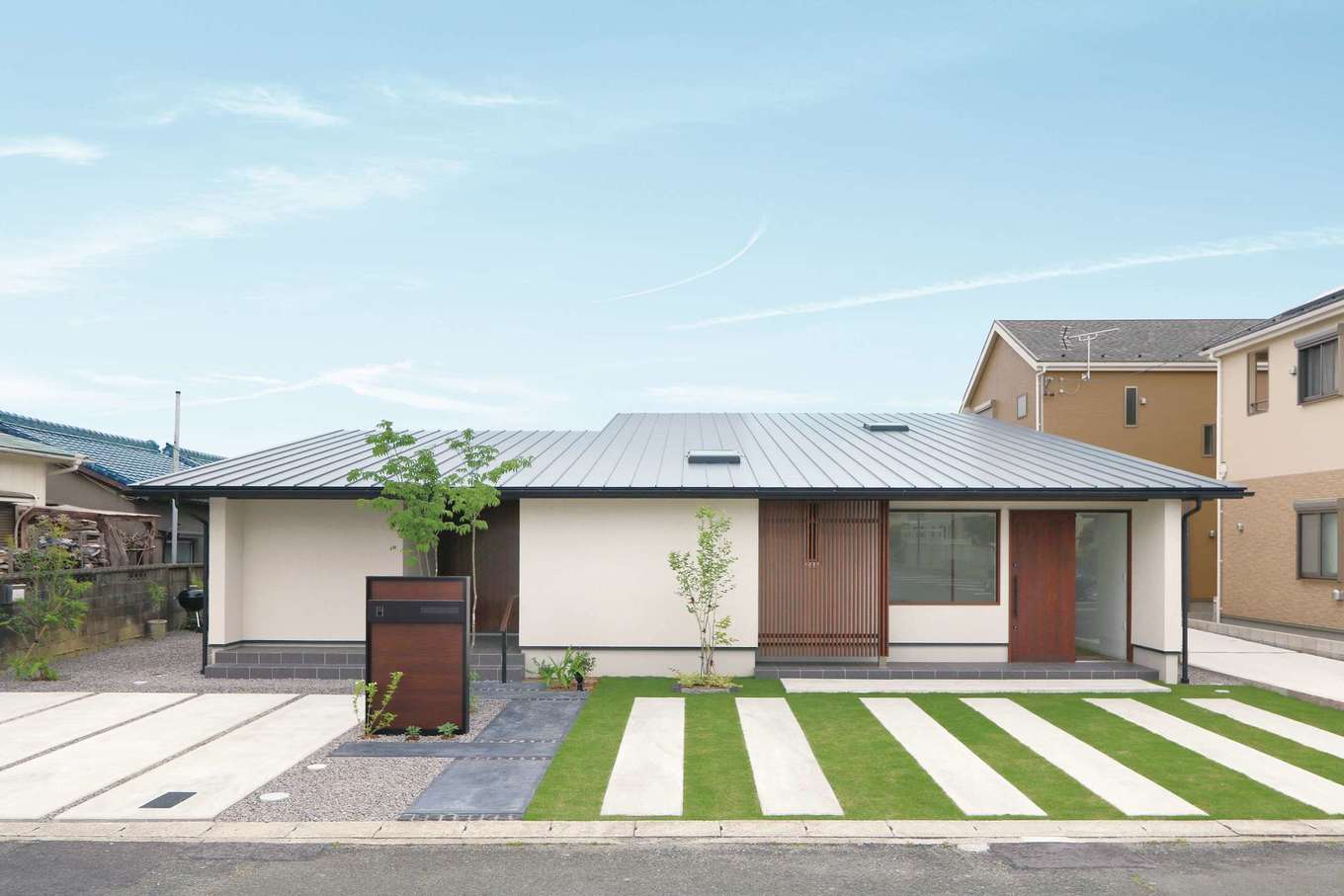 神谷綜合建設 カミヤの家【デザイン住宅、収納力、平屋】片流れの大屋根を抱く、堂々たる佇まいの外観。軒の高さをできるだけ低くし、塗り壁に杉の格子が映える洗練されたデザイン。ギャラリーの入口が分かるよう、住居の玄関はあえて引き込ませ、目立たないように配慮