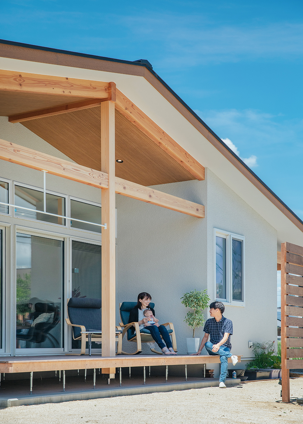 小幡建設【デザイン住宅、収納力、趣味】深い軒と十字の立派な木の柱が印象的な平屋の外観。この軒が日差しを遮り、涼しいウッドデッキでくつろぐGさん家族。奥さまの実家が農家ということもあり、庭に家庭菜園を作って子どもに「食育」を実践する予定