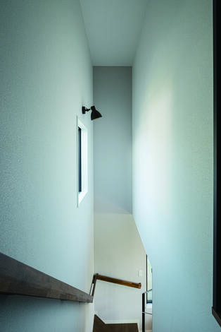 吹抜けの階段に窓を設け、電気をつけなくても明るい。太めの手すりがアクセント