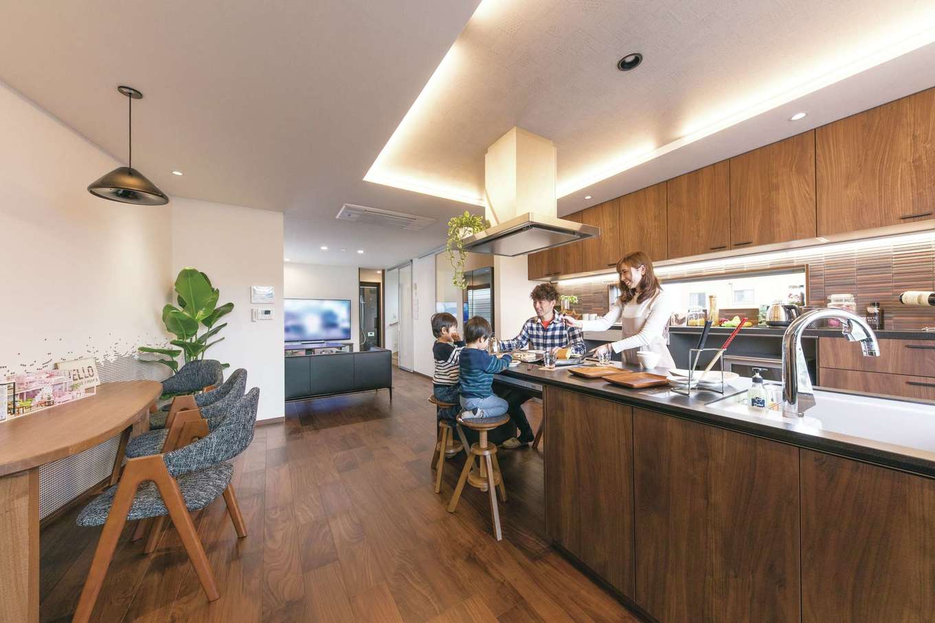 建築システム（狭小住宅専門店）【浜松市中央区助信町9-16・モデルハウス】シックなヴィンテージ調にまとめられたLDK。門型フレームを採用し、2階部分はワンフロアの大空間を実現。キッチンダイニングは縦の広がりを生み出す上げ天井にし間接照明で空間を演出する。壁一面の大容量収納に加えて、アイランドキッチンにもたっぷりの収納スペースを完備。すっきりと片付けられる設備選びの参考にしたい