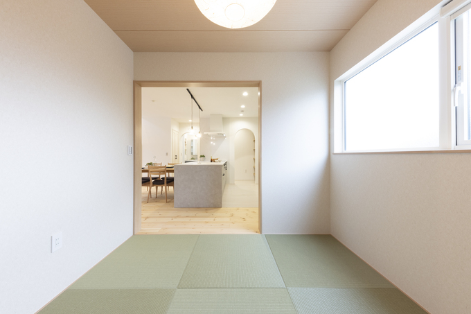 リビングの一角に設けられたおしゃれな畳スペース。窓から自然光が差し込み、和の落ち着きを演出している。リラックスするための快適な空間である。
