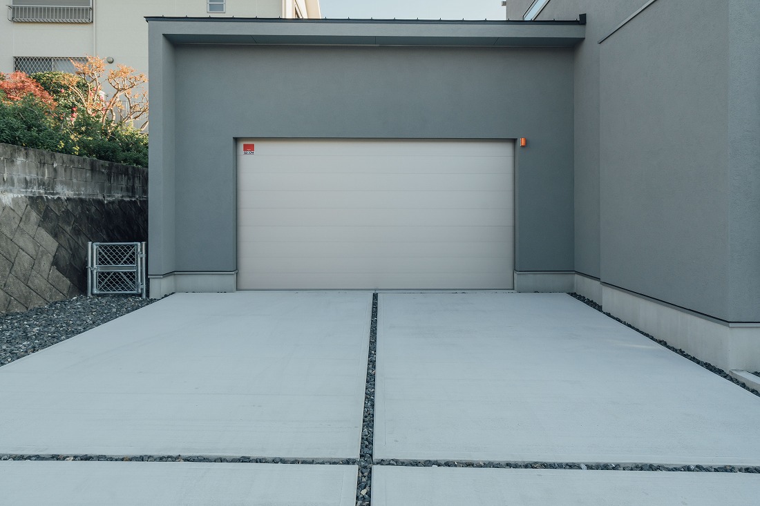 チェックハウス｜住宅にビルドインされたガレージ。車の出し入れがしやすく、外観と調和したデザインが特徴的である。
