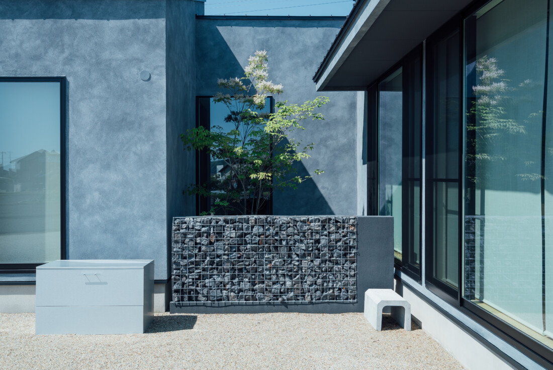 チェックハウス｜建物に囲まれたプライベートな中庭。石垣がアクセントとなり、植栽とともに落ち着いた雰囲気を演出している。
