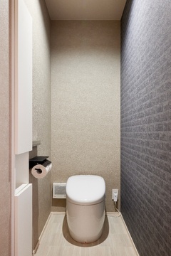 グレージュ系のクロスとアクセントのレンガ調クロスが上品に調和した、落ち着きのあるトイレ。空間をすっきりと保つ収納も完備され、機能性とデザイン性を両立した仕上がりに。