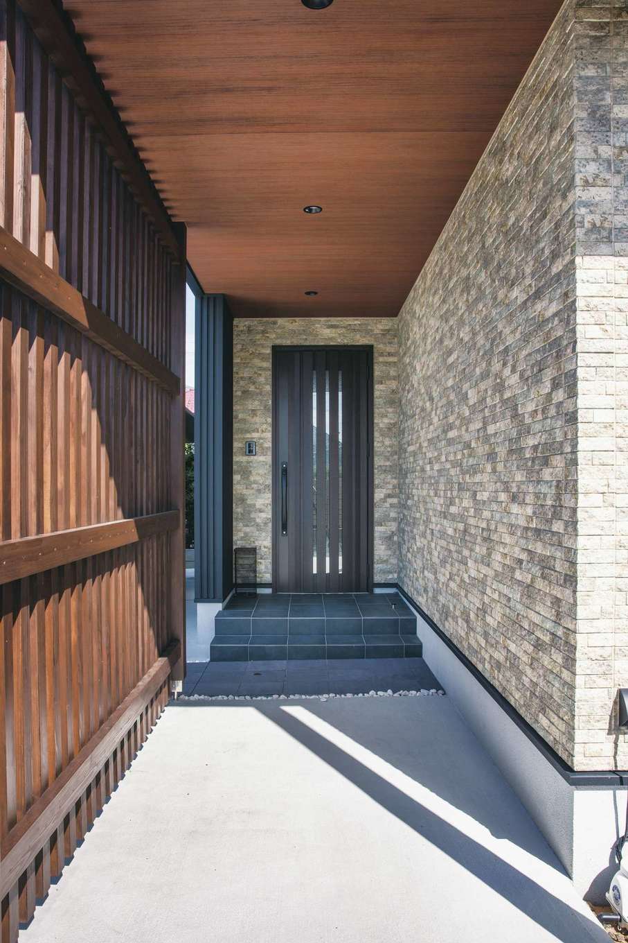 コットンハウス【デザイン住宅、子育て、省エネ】格子と壁で隠した玄関アプローチが、どことなくミステリアスな印象を放つ
