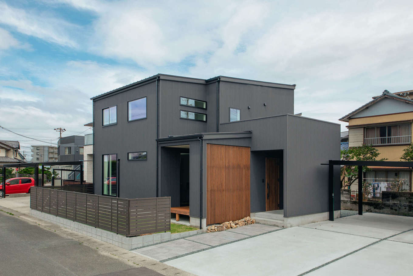 DAITOKU（大得工務店）【デザイン住宅、間取り、スキップフロア】外壁にメンテナンス性の高いガルバリウム鋼板を使ったM邸。庭とウッドデッキに目隠しのルーバーフェンスを採用。片流れの屋根に7.41kWの太陽光発電を搭載し、電気代を抑える工夫も