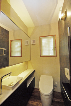 トイレの閉鎖感をなくすため大きな鏡を取り付けて広さを演出。壁には湿気やニオイを吸収するエコカラットタイルを貼った