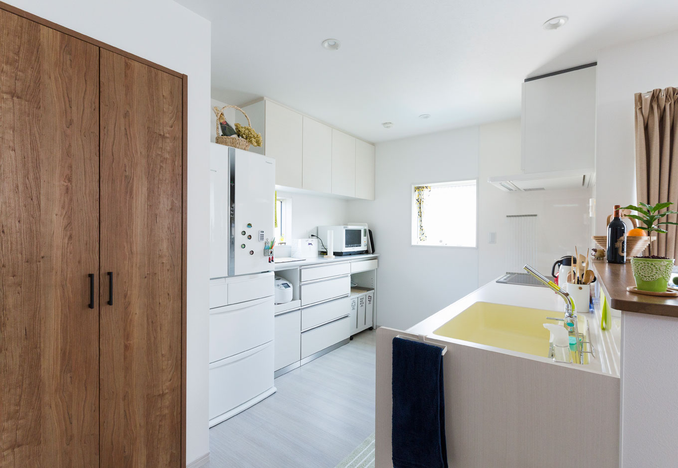 建築システム（狭小住宅専門店）【収納力、間取り、ガレージ】キッチン、換気扇フード、食器棚、冷蔵庫、清潔感のある白色で統一したため、より一層 開放感が広がった