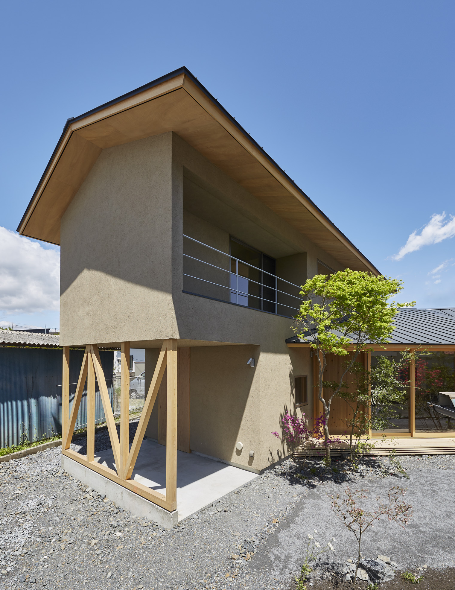 イケダ工務店｜シンプルでモダンな外観を持つ2階建て住宅。木製の柱とベランダが特徴的で、自然との調和を感じられるデザイン。