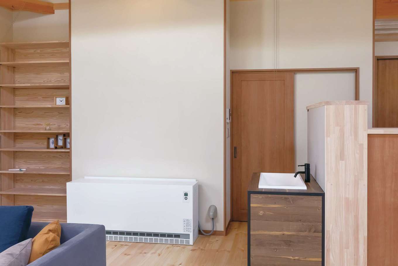 住まいるコーポレーション【デザイン住宅、自然素材、平屋】書棚の隣に蓄熱暖房機を設置。これ1台で冬は家中がぽかぽかと暖まる。夜間の電力を利用するので省エネ性にもすぐれている