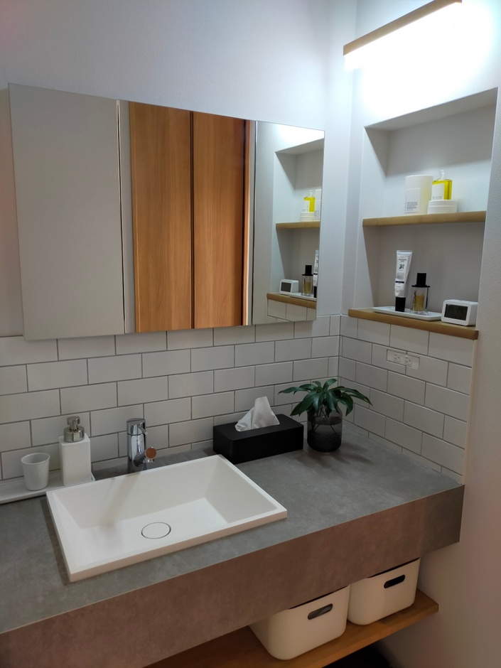 キッチンと脱衣室の間に設けられた洗面スペース。サンワカンパニー社のモルタナ洗面にサブウェイタイルを組み合わせ、モノトーンでスッキリとした印象に。