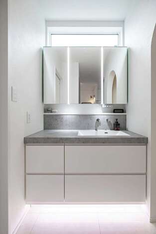 造作洗面台は朝の身支度も気分が軽くなる仕上がり。下部には間接照明