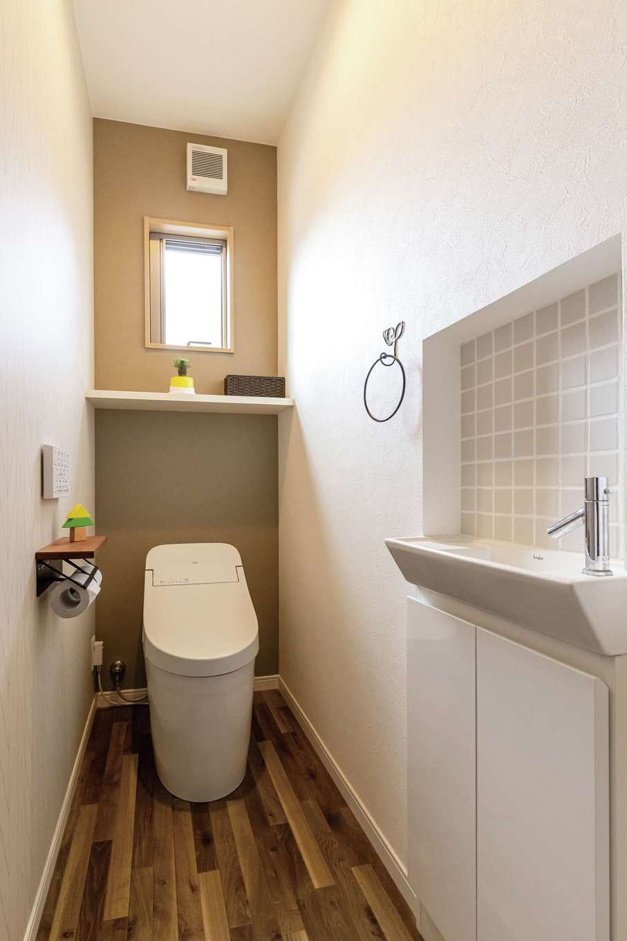 甲静ハウジング【子育て、収納力、間取り】1階のトイレ。タイル調のクロスを貼って、空間のアクセントに。窓の大きさや棚の高さは現場で確認して決めた