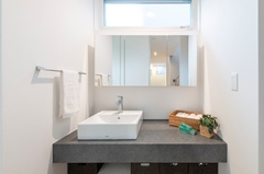 洗面台の上部に設けたスリット窓から明るい光が差し込む洗面スペース。横並びで準備ができるスペースを確保しました。