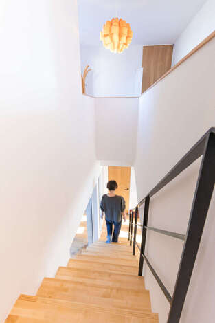 以前の住まいから使っていたという照明がアイアンのスケルトン階段によく似合う。階段上のホールには、奥さまと娘さんが使うピアノを置く予定