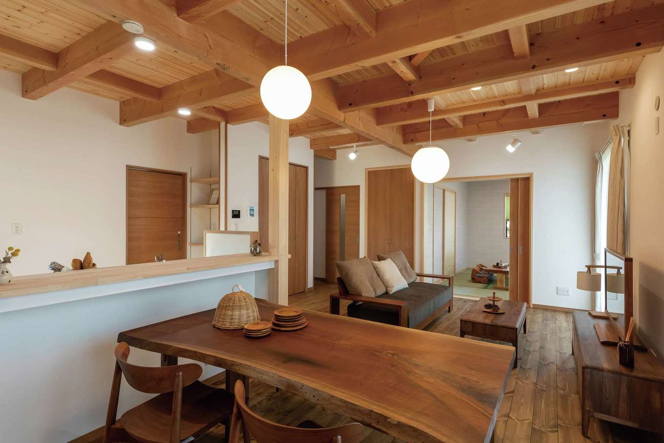 住まいるコーポレーション【デザイン住宅、和風、自然素材】対面キッチンの正面に設けたダイニング。天然木のカウンターは、奥さまの身長に合わせて設置。作業の手元を隠すと同時に、ダイニングとのやりとりがしやすい高さに調整した。プランニング段階での細やかな配慮が、暮らしやすさを向上させている