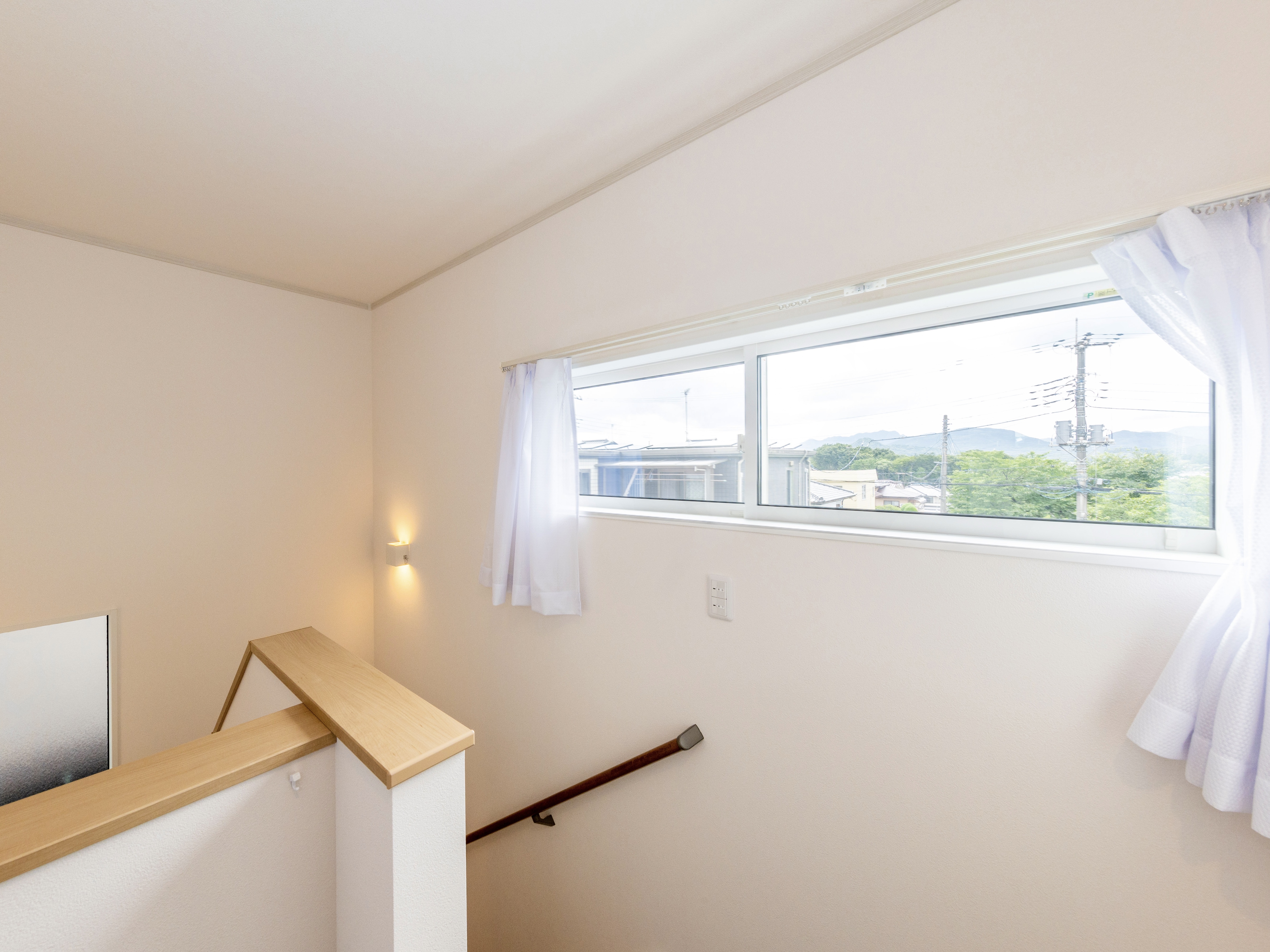 エスホーム｜住宅内の階段スペース。大きな窓から自然光が差し込み、明るく開放的な雰囲気。階段手すりはシンプルなデザインで安全性も考慮されている。