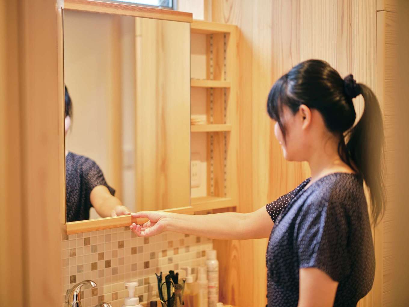 アクトホーム【自然素材、省エネ、間取り】無垢とタイルの洗面台も造作。鏡はスライドする仕掛けで、背後のスペースまで無駄なく活かされる