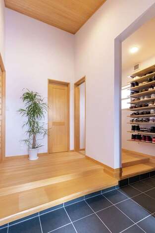 座って靴を脱ぎ履きできるように一枚板の式台を玄関に設置。正面の扉を開ければパントリー、左はリビングへと続く