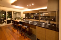 広々としたキッチンには、カウンターチェアが並ぶバーカウンターがある。背面収納は収納力も抜群で、機能面とデザイン性を両立している。