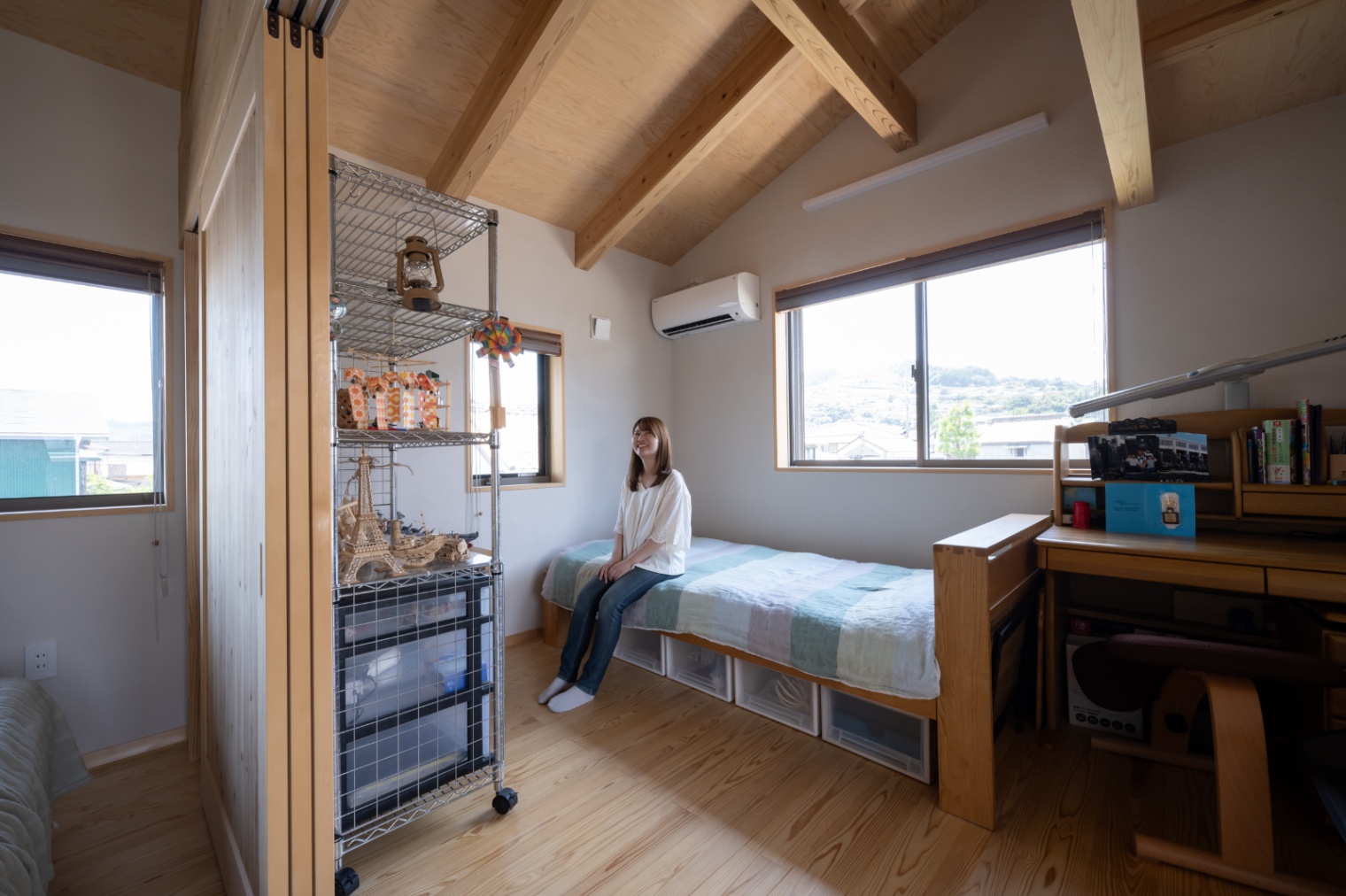 アクトホーム｜天井が高く、木の温もりが感じられる子ども部屋。机やベッドが配置され、勉強と休憩がしやすい環境が整っている。