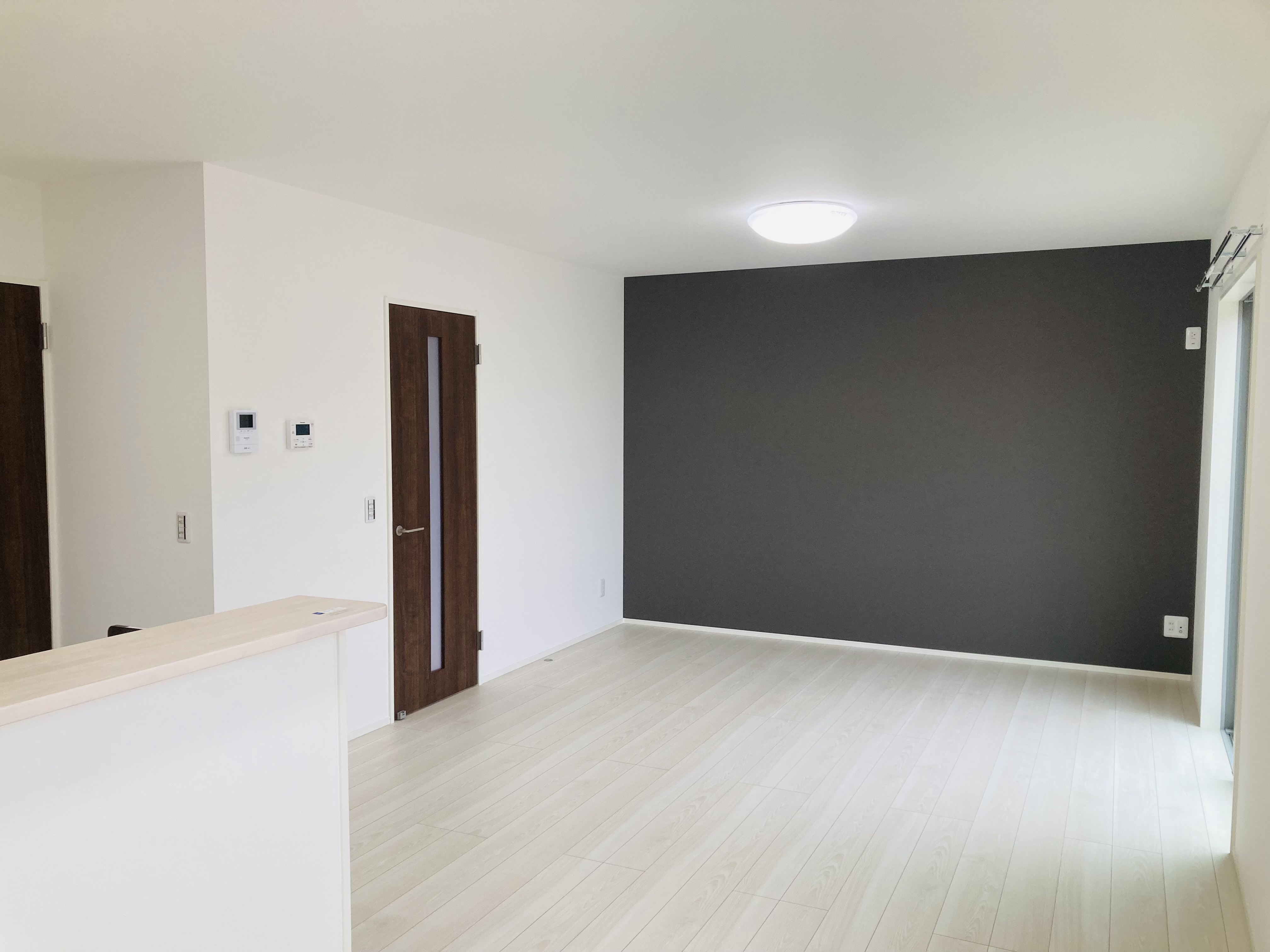 沢田建設｜シンプルでモダンなデザインのLDK。アクセントウォールが印象的で広々とした空間が広がる。室内に自然光がたっぷり入り、明るく居心地が良い。