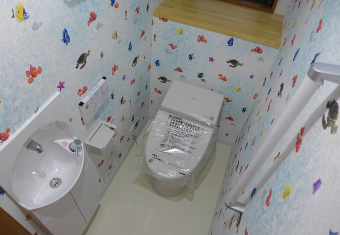 建築システム（狭小住宅専門店）【1000万円台、狭小住宅、ガレージ】ニモのかわいい壁紙のトイレ。海中を泳いでいる気分