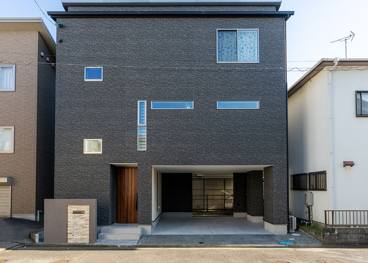 寺田工務店【収納力、狭小住宅、省エネ】22坪の土地に完成した木造三階建て。1階はインナーガレージ付きで、雨に濡れることなく玄関までアクセスできる。ブラックの外壁が住宅街の中で存在感を発揮。すっきりとした外観をよりおしゃれに見せている