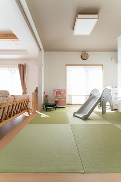 畳敷きの子ども部屋には滑り台が設置され、遊び心あふれる空間が広がる。柔らかな自然光が部屋全体を包む