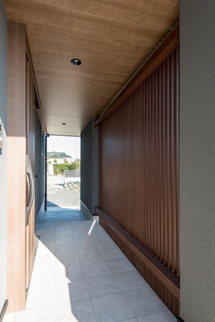 通りから玄関が丸見えにならないよう、格子で目隠ししたアプローチ。京都の町屋のような風情がただよい、帰ってくるたびにホッと落ち着く