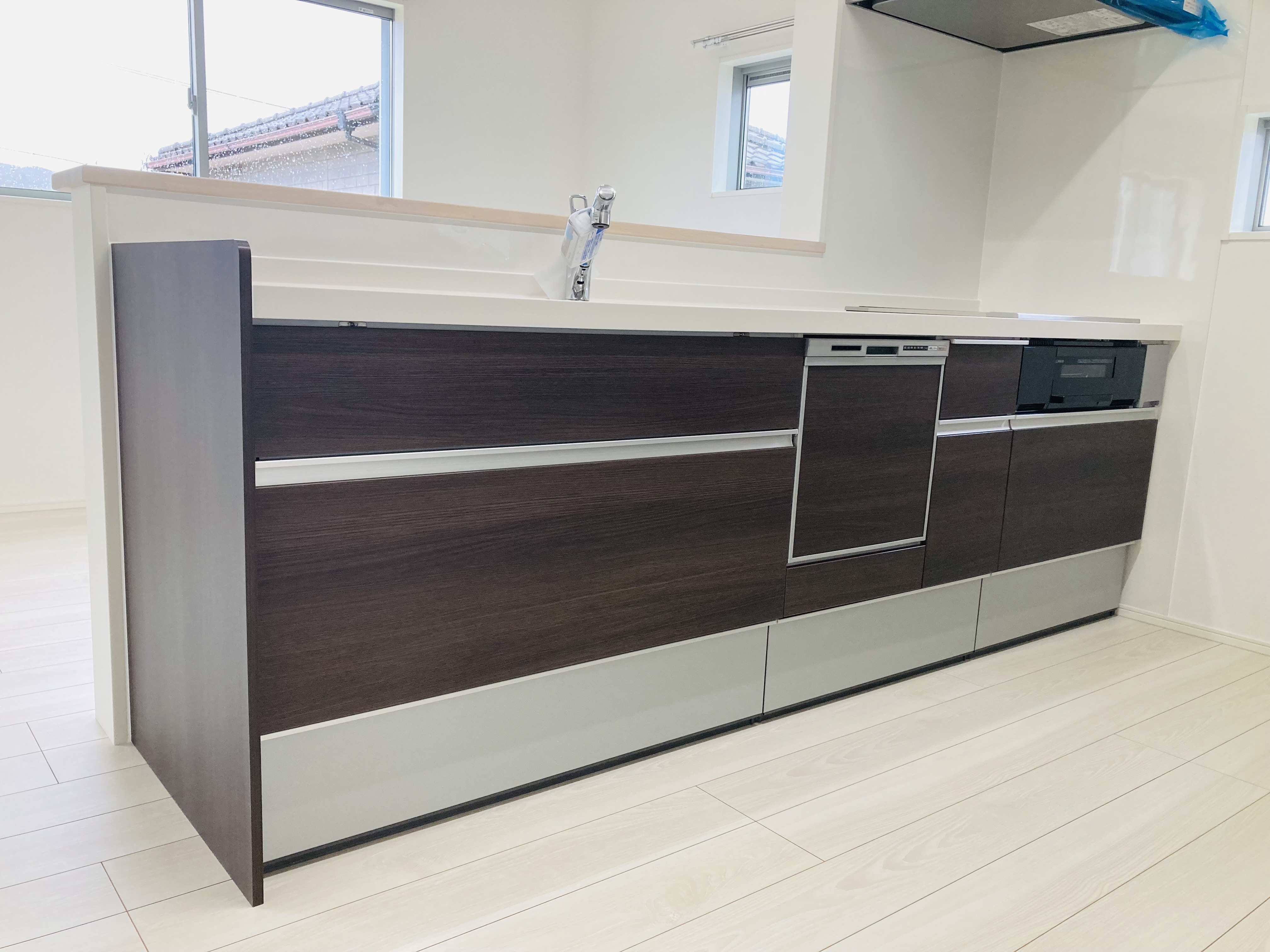 沢田建設｜モダンなデザインのキッチン。ダークウッドのキャビネットが白い空間に映え、スタイリッシュかつ機能的な印象を与える。