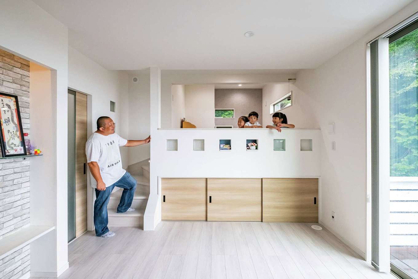 工藤建設【デザイン住宅、子育て、間取り】スキップフロアの中2階は子どもたちの大好きな遊び場所。腰壁にはガラスブロックをちりばめ、真ん中にはニッチ、扉部分には雛人形やファンヒーターなど大きい物が入る大収納空間