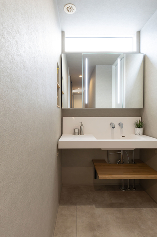 造作の洗面台はすっきり、シンプルなデザインに。下部をフルオープンにしているので、収納のレイアウトも自由自在。ハイサイドのスリット窓から自然光も取り入れる