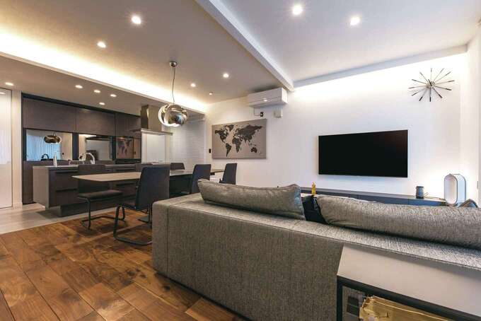 20畳を超えるLDKは気持ちにゆとりをもたらす。室内をモノトーンで統一しながら、無垢の床と珪藻土の塗り壁を採用したことで、温かみのある住みやすい空間に。Bluetooth接続のLED照明はスマホで簡単に調光できる