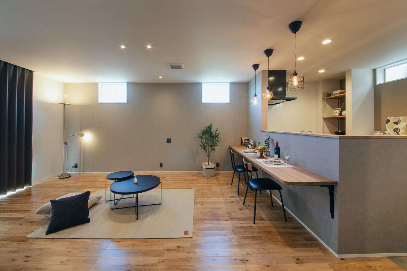 DAITOKU（大得工務店）【デザイン住宅、子育て、間取り】リビングに座って、ローテーブルで食卓を囲むスタイル。造作のキッチンカウンターでは、カフェタイムを楽しんだり、将来子どもが勉強したりと多用途に使うことができる。肌触りのいい床は無垢のナラ材で、経年変化も楽しみだ