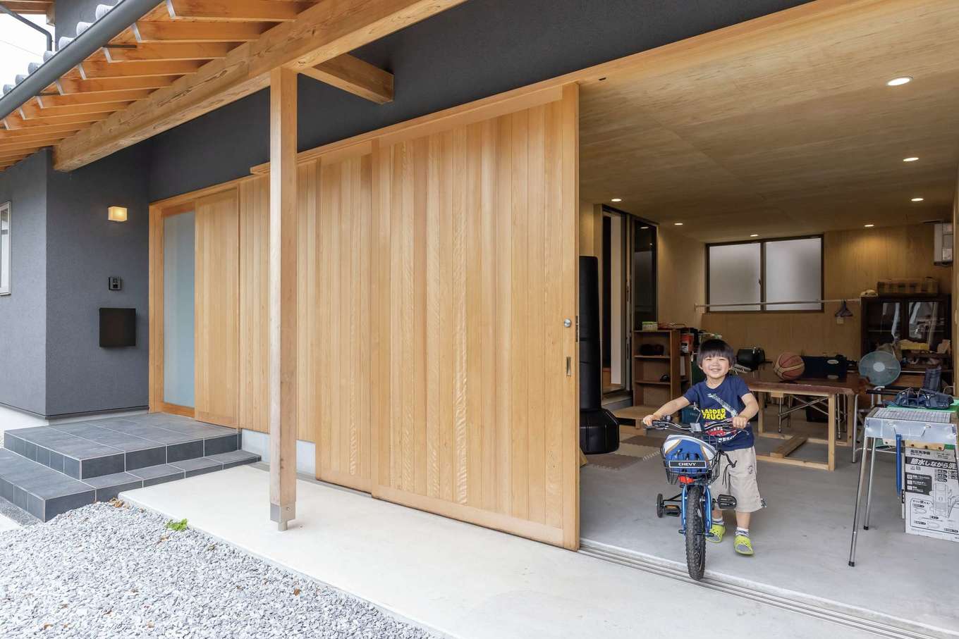 神谷綜合建設 カミヤの家【デザイン住宅、和風、間取り】ヒノキの引き戸を開けると12畳のインナーガレージが登場。現在はご主人がDIYをしたり、お子さんの遊び場になったり、家族みんなでBBQを楽しんだりとマルチに活躍。軒の化粧垂木が凛とした佇まいを生んでいる