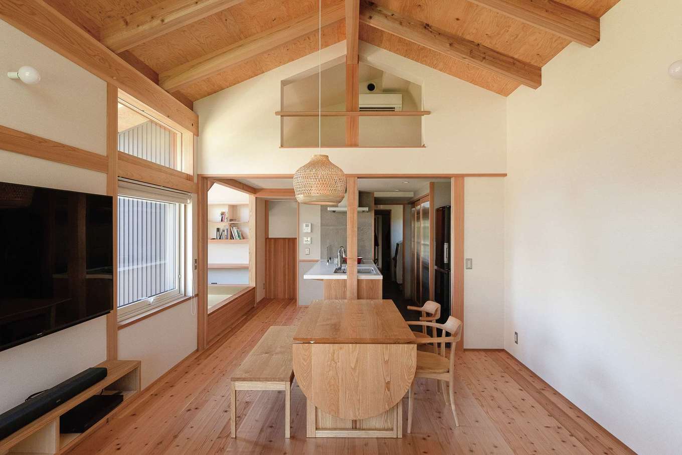 石牧建築【自然素材、間取り、平屋】開放感あふれる登り梁のリビング。床と天井は天竜杉。折り畳みテーブル付きのダイニングテーブルとベンチは『石牧建築』の造作