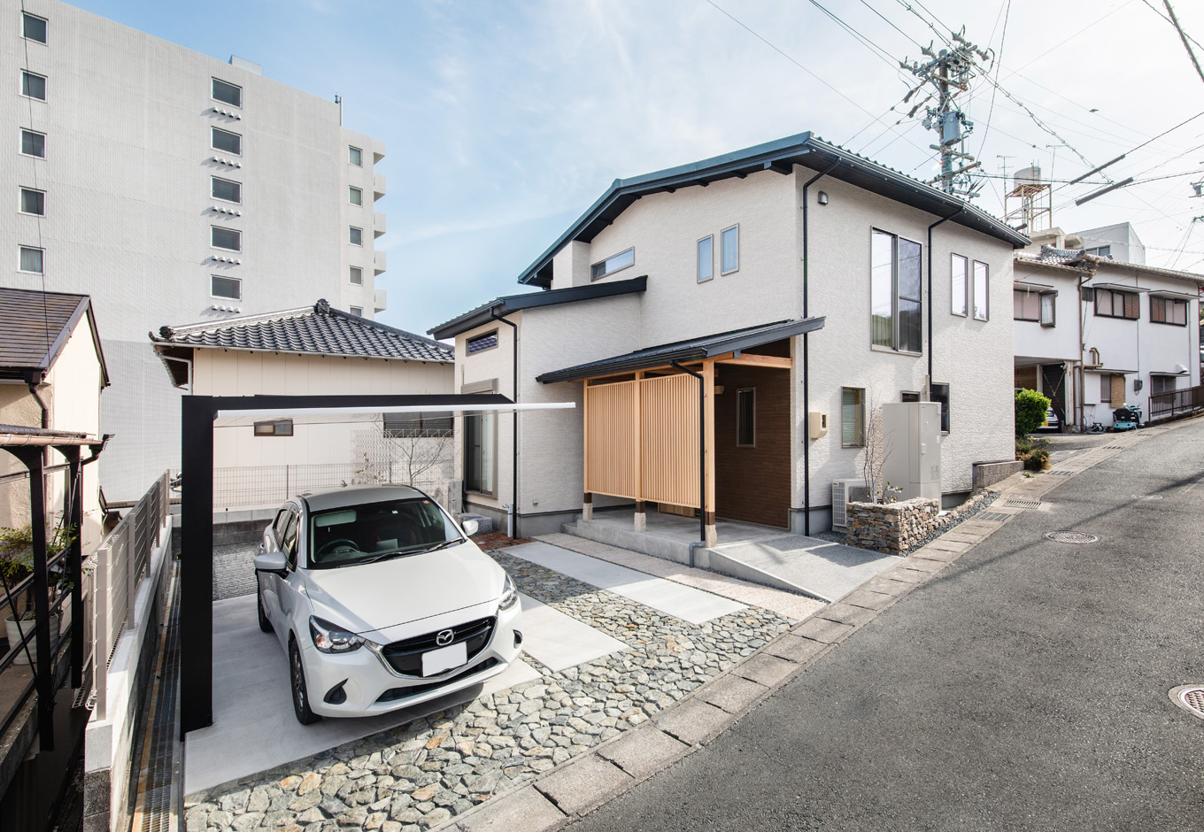 瀧口建設｜築50年以上経っているとは思えないほど、美しく再生した外観。室外機が1台しかないので、見た目もすっきり。カーポートや庭のしつらえにもこだわり、新築同然の佇まいをみせている。将来的に車椅子に乗ったままでもストレスなく玄関にアクセスできるよう、スロープ状のアプローチに