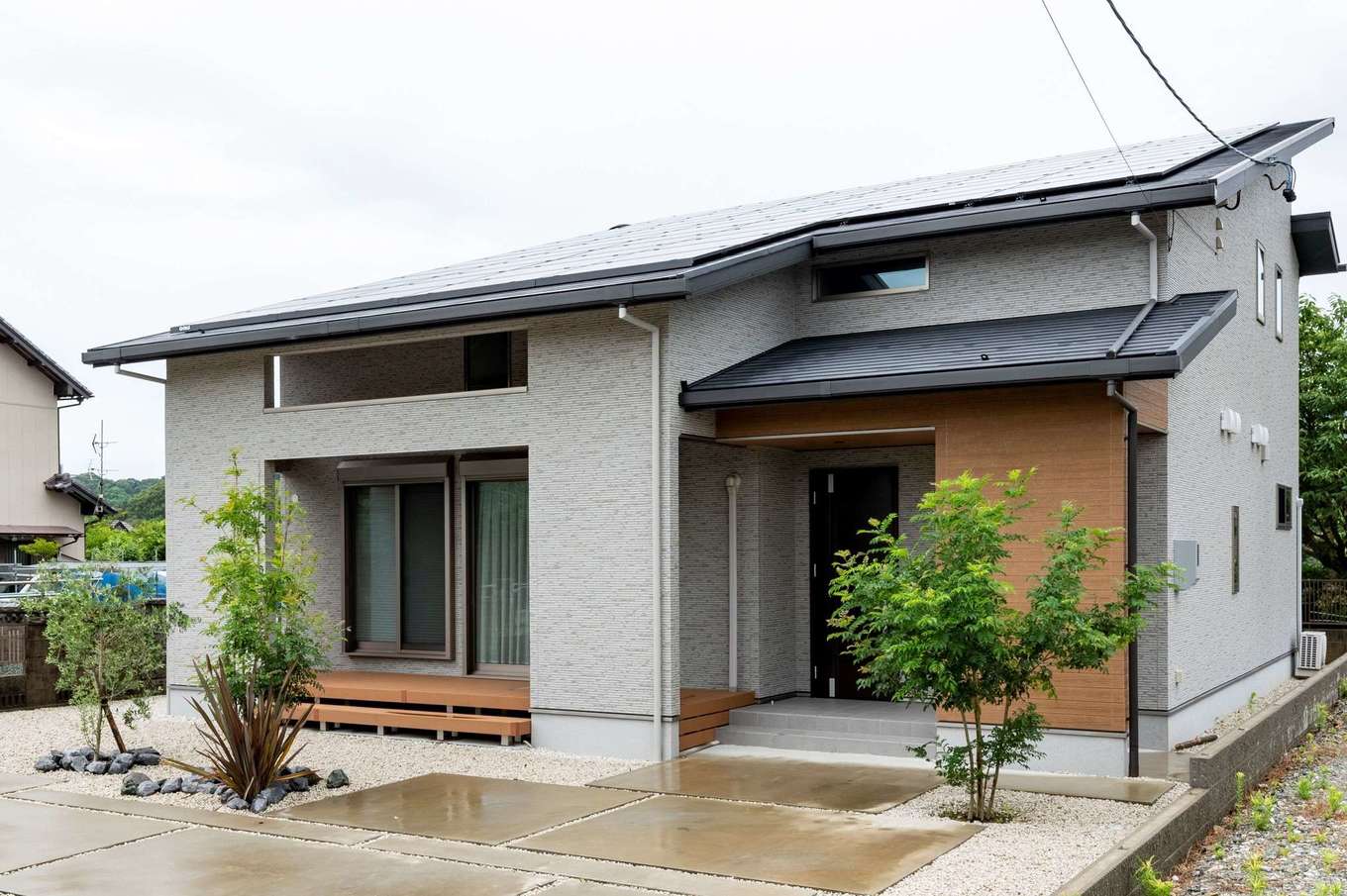 AQURA HOME（アキュラホーム）【デザイン住宅、収納力、間取り】片流れの屋根に20kWの太陽光パネルを搭載した平屋風の外観。グレーの外壁は太陽の光が当たると汚れを分解し、雨で簡単に汚れが落ちるKMEWの光セラを使用。深い軒が直射日光を遮り、太陽高度の低い冬は室内の奥まで光を届けるパッシブデザインに