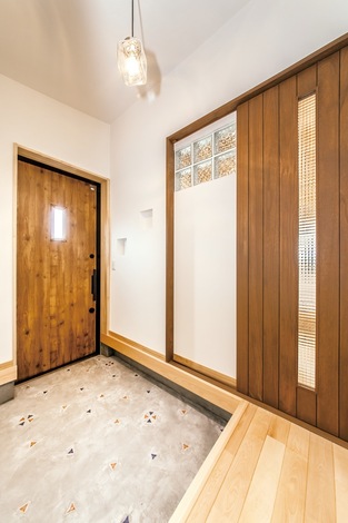 引き戸のチェッカーガラスやガラスブロックから、リビングの明かりが届く。玄関ホールと、そこから続くポーチにはカラフルなタイルをはめ込んだ