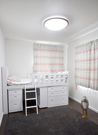 こども部屋。ピンクのボーダー状のカーテンと白い家具で女の子らしい雰囲気に