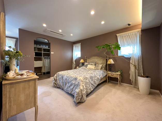 シンプルで落ち着いたインテリアの寝室。広々とした空間にベッドやサイドテーブルが配置され、快適な居住空間が広がる。