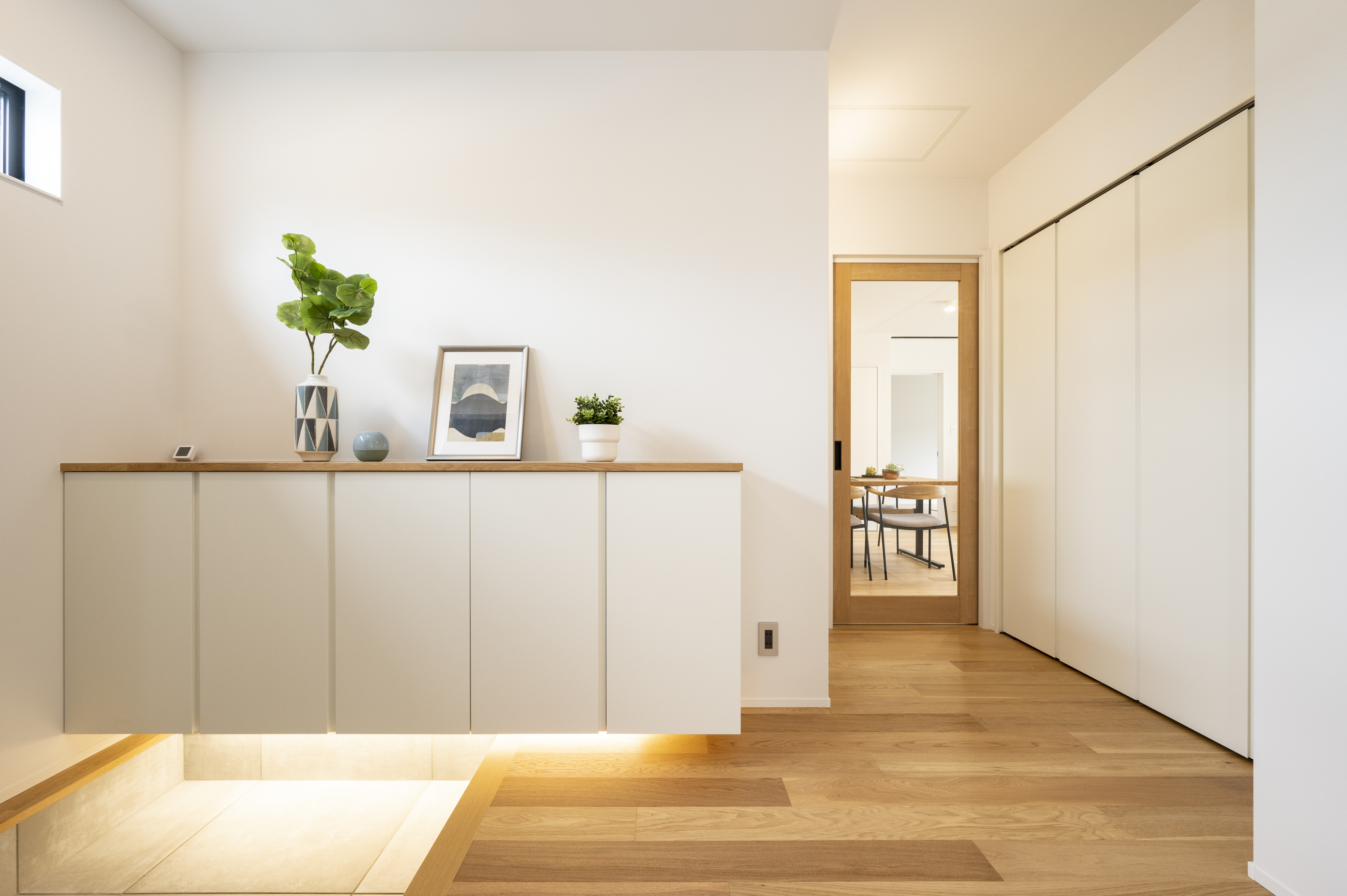 ニッケンホーム｜硝子のリビングドアと床を照らす間接照明で、玄関の圧迫感を解消