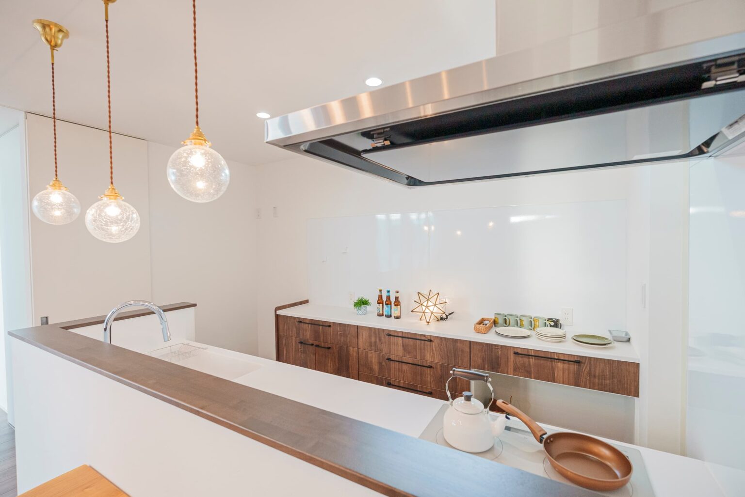 Touch House（タッチハウス）【子育て、間取り、平屋】木目調のデザインが柔らかな印象をLDKにもたらすキッチン。ペンダントライトの光が柔らかく空間を照らし出す