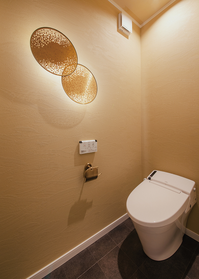 玄関から近い場所に配置したトイレ。照明器具とクロスの色を工夫して、シンプルな中にも上質なしつらえを表現した