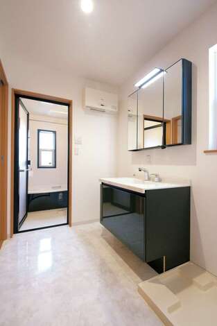 玄関からもキッチンからも短い動線で行けるサニタリー。黒い洗面台と浴槽が空間を引き締めている