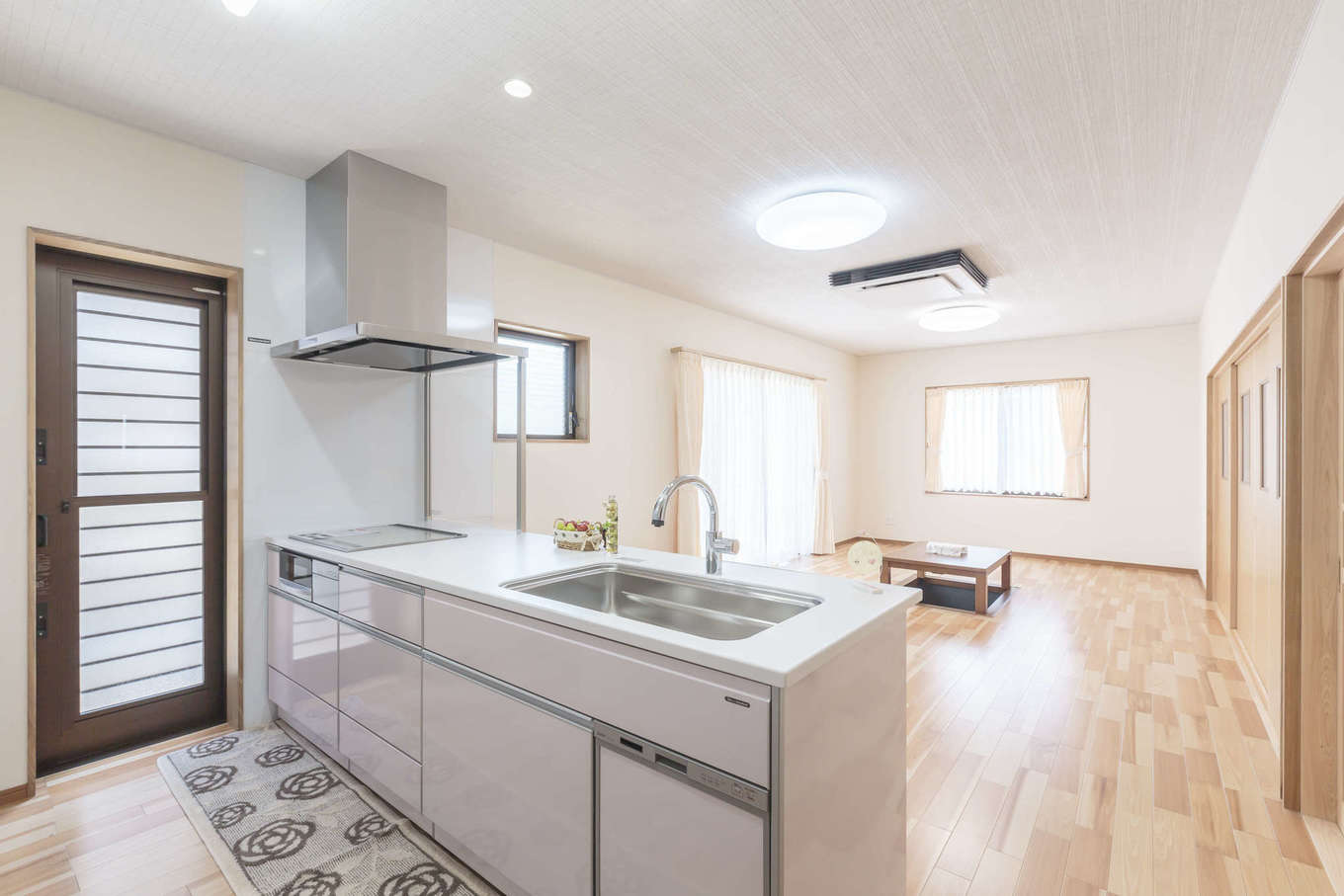 まちの大工さん 鈴木工務店【夫婦で暮らす、間取り、平屋】対面キッチンからは室内全体が見渡せて、気持ちよく調理や片付けができる。桜色のキッチンは奥さまのお気に入り。シンプルな室内にやさしい雰囲気をもたらしている