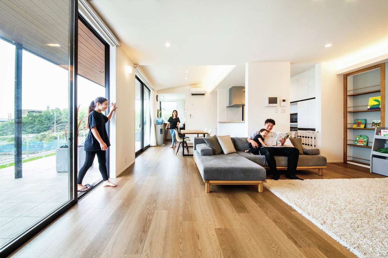 内田建設【デザイン住宅、趣味、建築家】ワイドスパンのLDKは24畳の大空間。床から天井まで届く大きな開口部がリビングとテラスをフラットにつなぎ、より開放感が生まれた。キッチンからテラスまでの動線がラクなので、BBQの準備や後片付けも簡単。テラスの軒を深く伸ばしたことで、夏の直射日光を遮り、太陽高度の低い冬は、キッチンまで光が届く。高台の立地で、遠くの海までが見渡せて気持ちいい