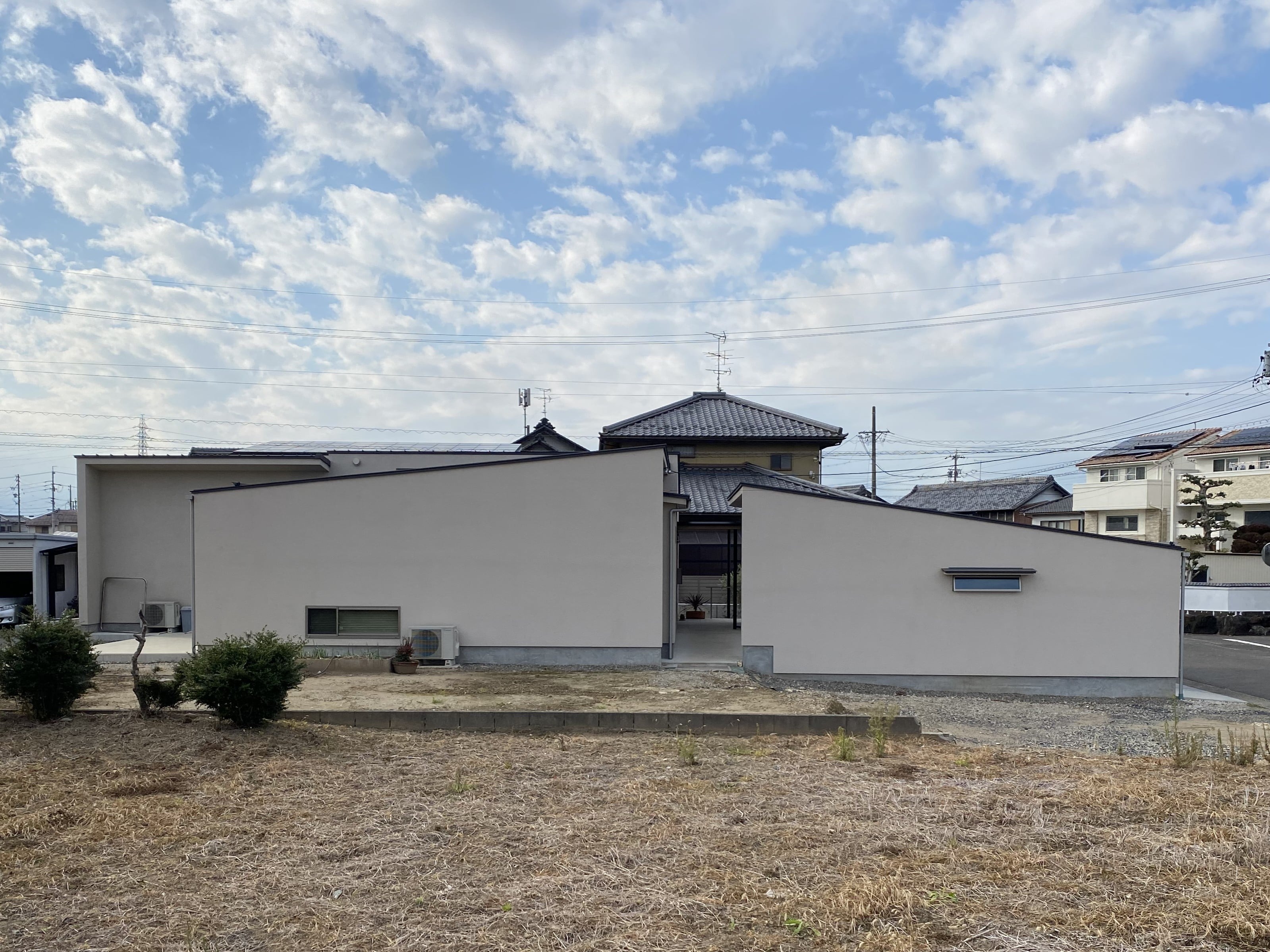 安田住宅｜安田建築設計室｜住居棟と車庫棟 それぞれから構成された片流れ屋根が特徴の外観。直線的に広がる建物が周囲の景観に調和しつつも、その独特なシルエットで存在感を放つ。